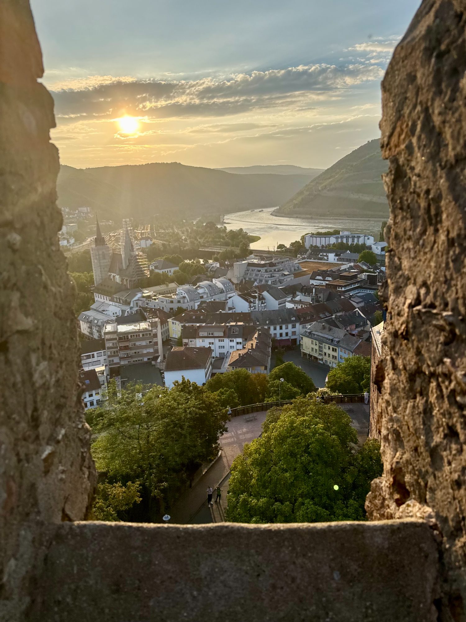 The Rhine valley and a riverside town at sunset, seen through a hilltop castle window