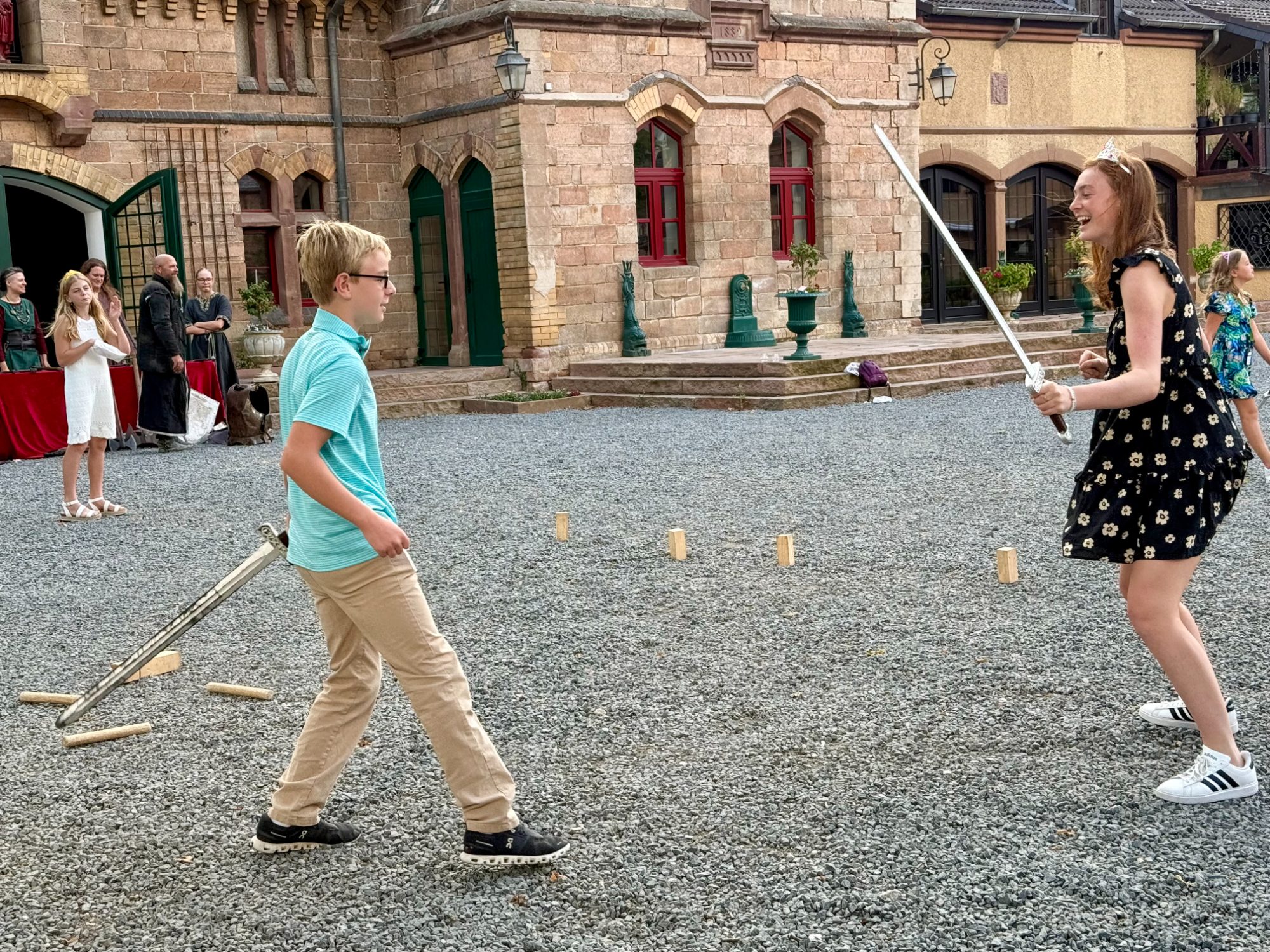 Two of the teens dueling with prop swords during medieval games at a private castle