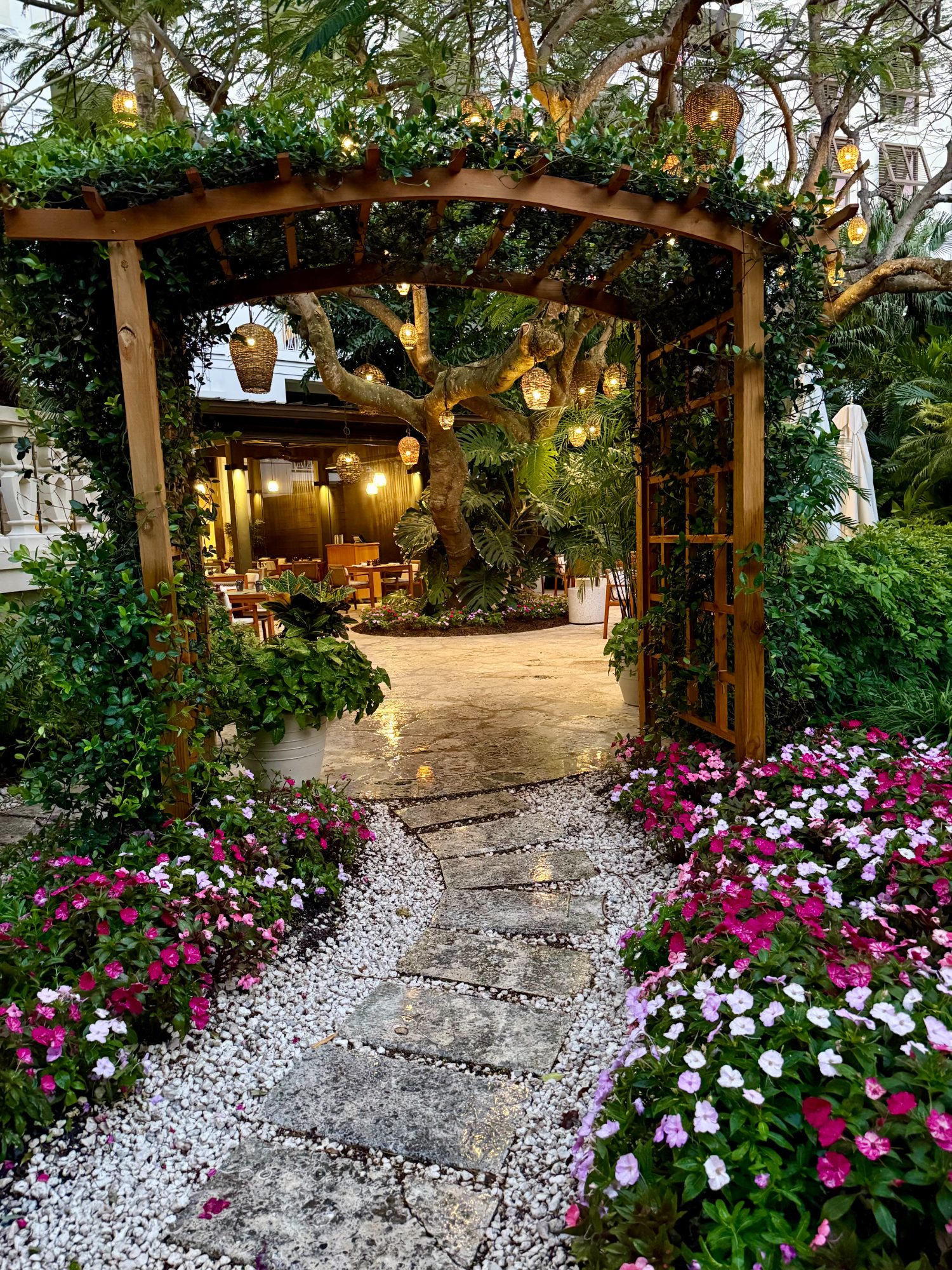A lantern-lit garden path leading into a restaurant at dusk