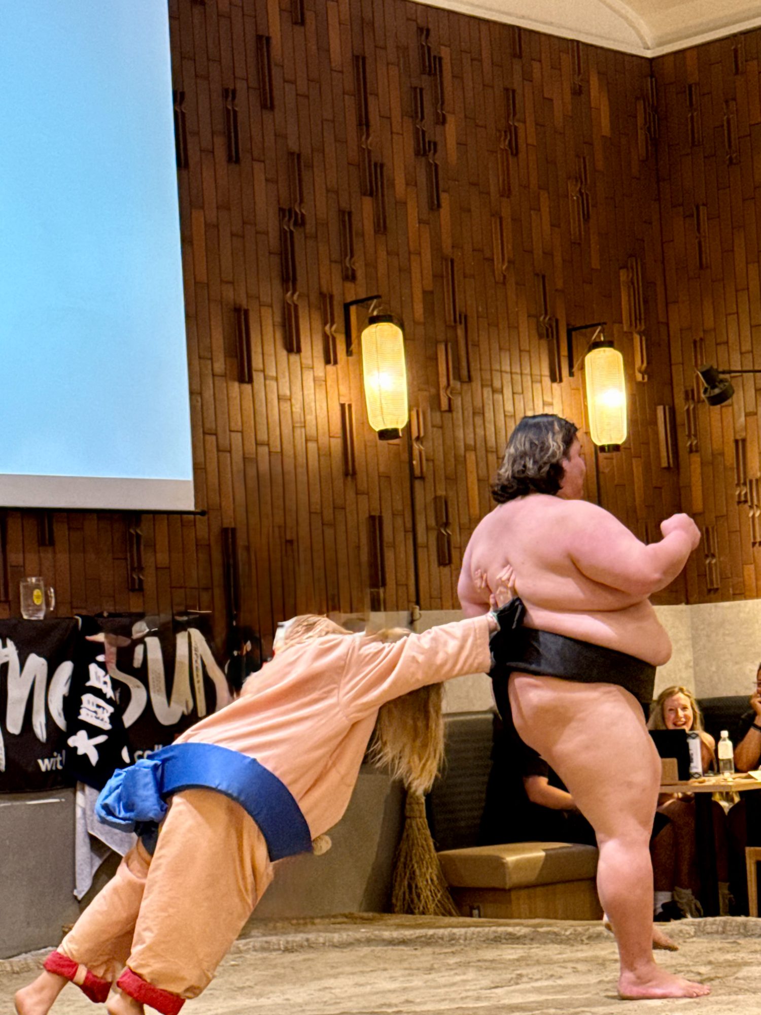 A family member in an inflatable sumo suit taking on a real wrestler